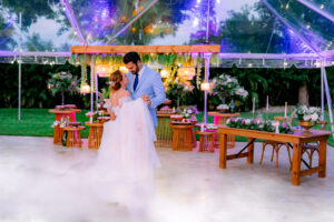 Couple sharing their first dance under a clear tent with lavender décor, florals, and glowing lights at Saint Patrick Palace.