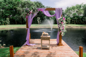 Lavender-draped wooden ceremony arch with floral accents overlooking the pond at Saint Patrick Palace.