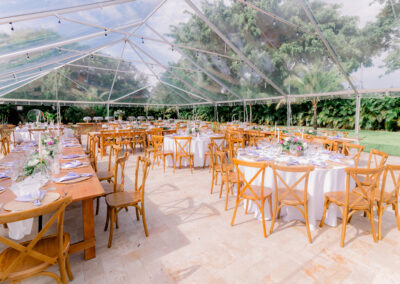 Clear tent outdoor reception with wood chairs, pastel florals, and summer greenery at Saint Patrick Palace.
