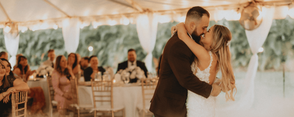 Bride and groom sharing a romantic first dance with the "dancing on a cloud" fog effect inside a luxury reception tent at Saint Patrick Palace in Davie, FL.