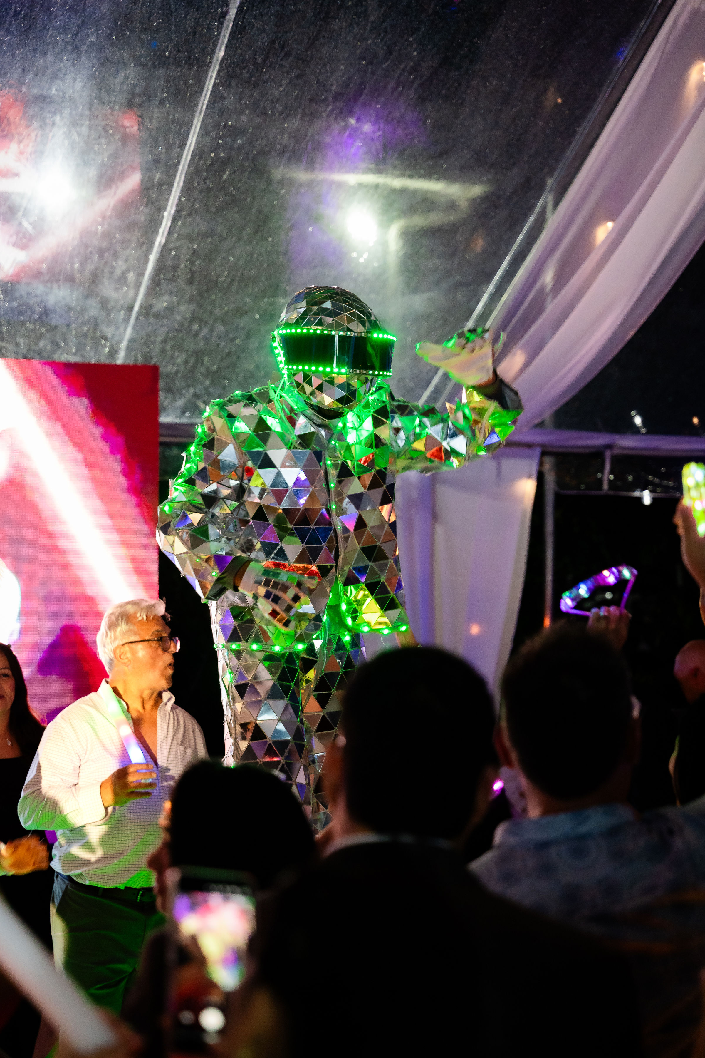 Close-up of LED robot entertainer with mirrored panels and green lights at a quinceañera celebration.