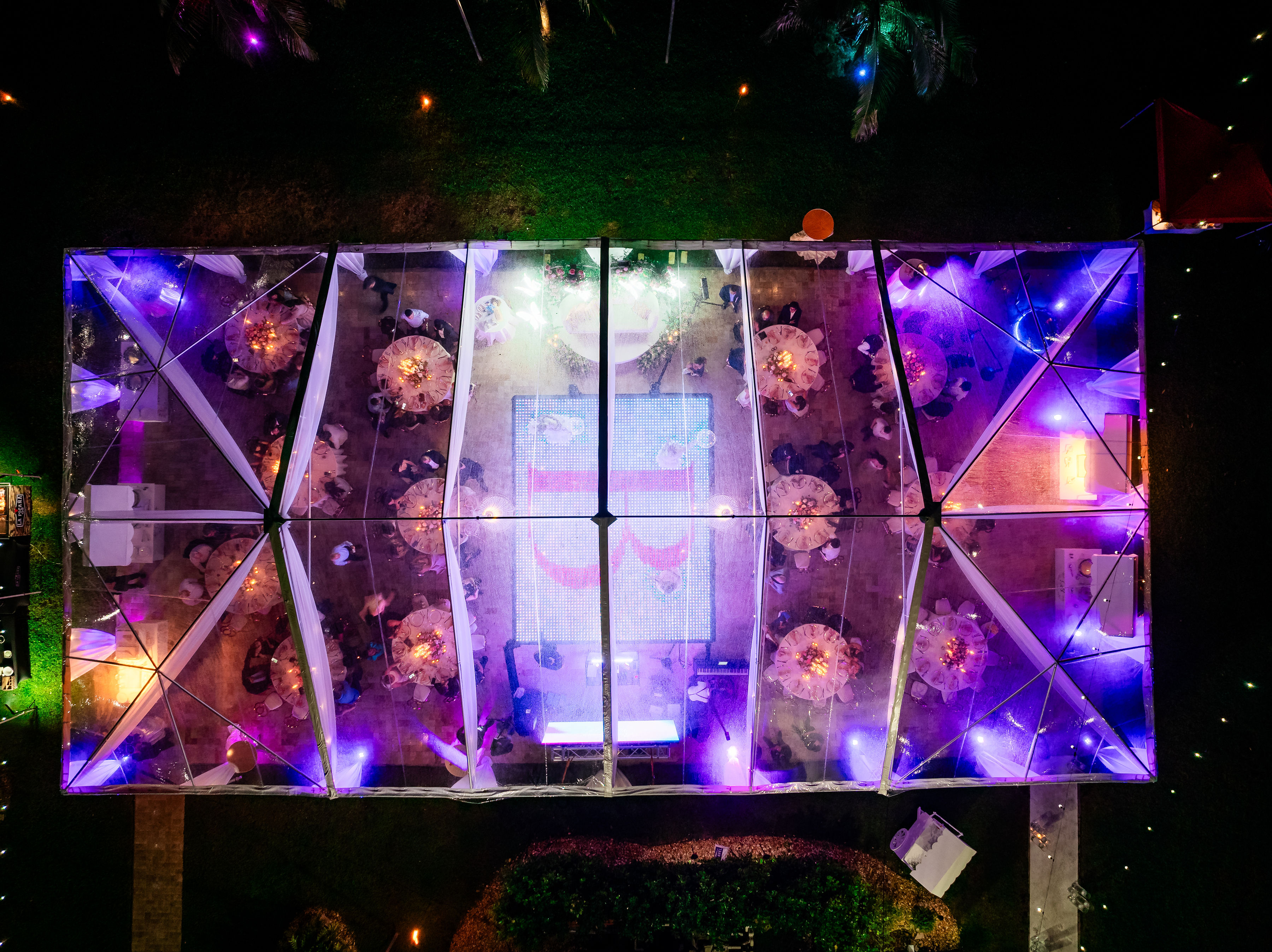 Overhead nighttime view of a rose gold quinceañera LED dance floor inside a clear-top tent at Saint Patrick Palace.