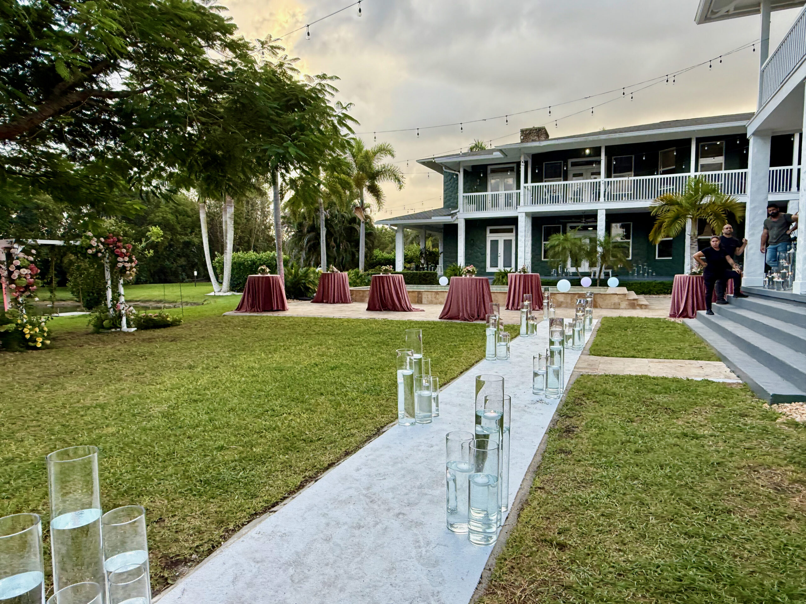 Candle-lit walkway leading to floral garden and estate veranda at Saint Patrick Palace, South Florida.