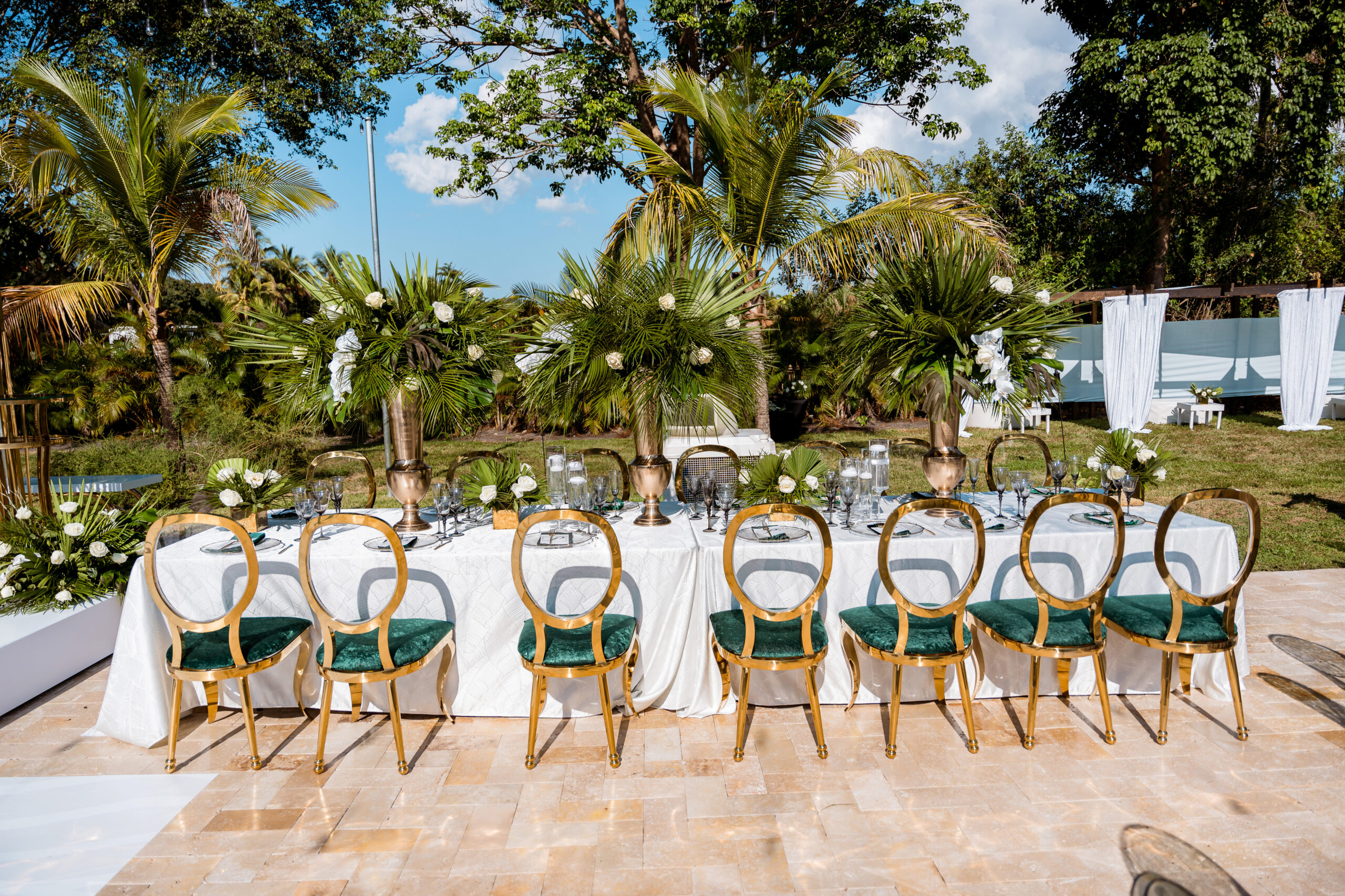 Grand head table with gold chairs, emerald seating, and palm centerpieces at Saint Patrick Palace in Davie, FL