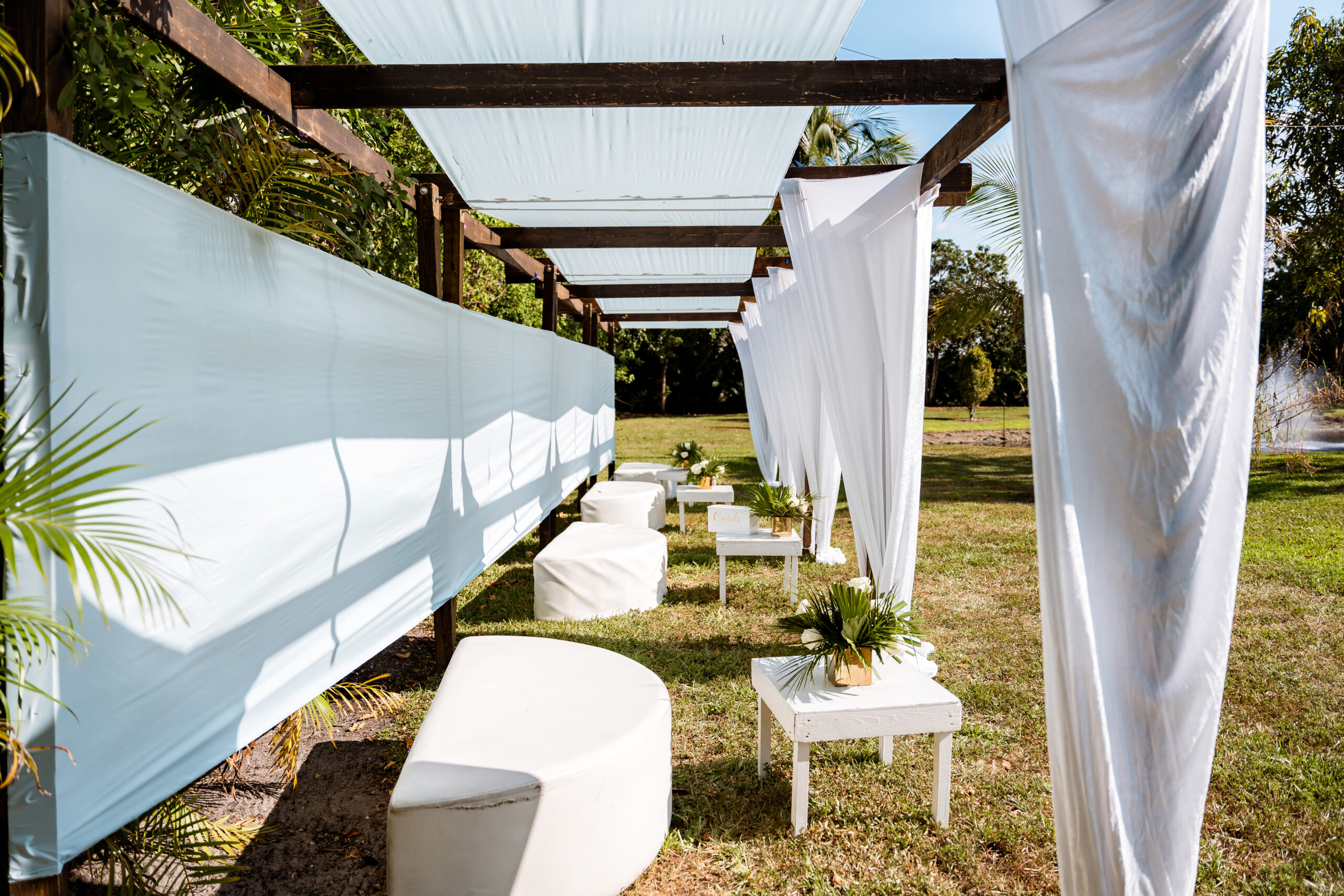 Outdoor lounge canopy with white draping, modern seating, and tropical greenery at Saint Patrick Palace in Davie, FL