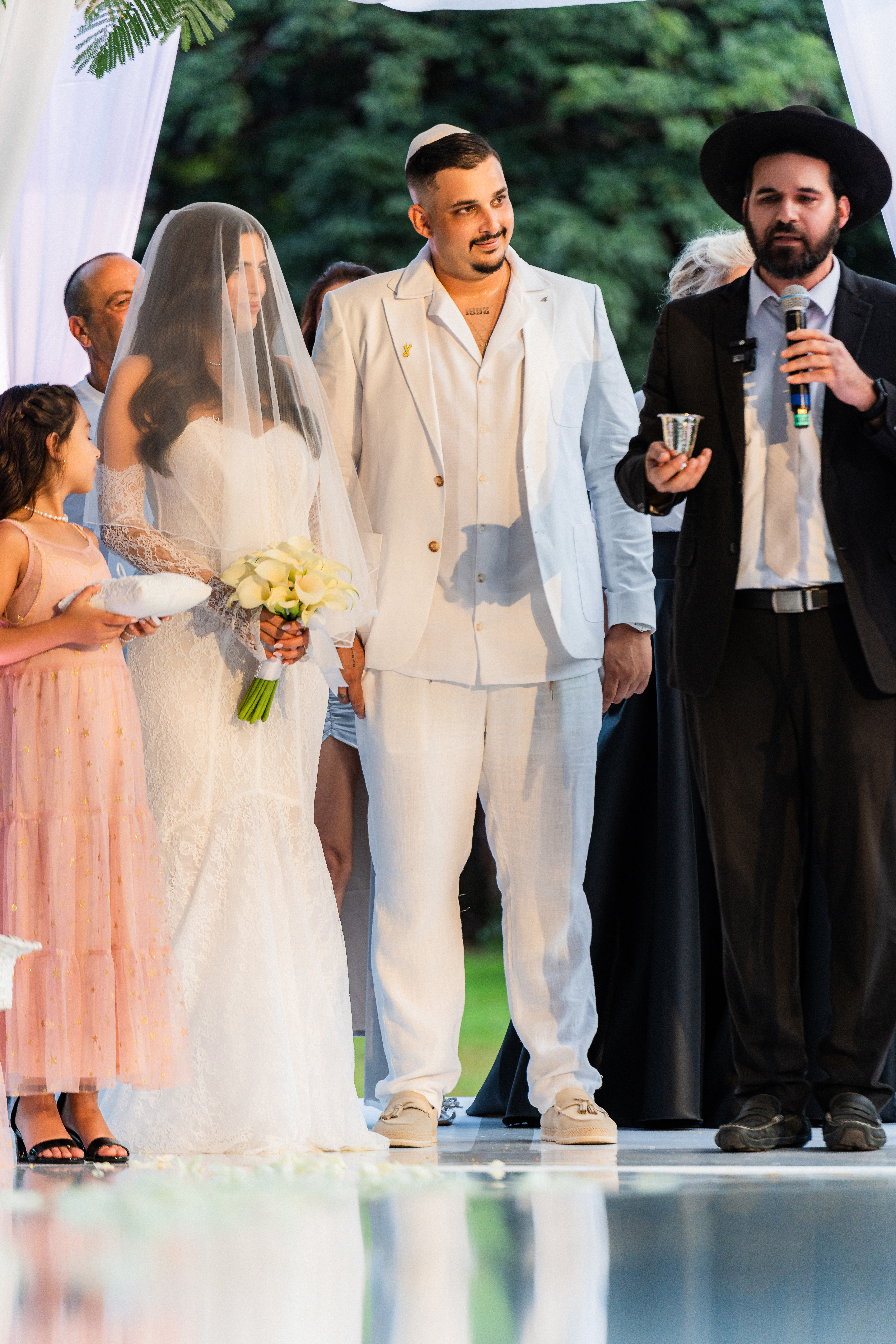 Couple standing beneath the chuppah during a classic ceremony at Saint Patrick Palace, surrounded by loved ones and soft evening light.