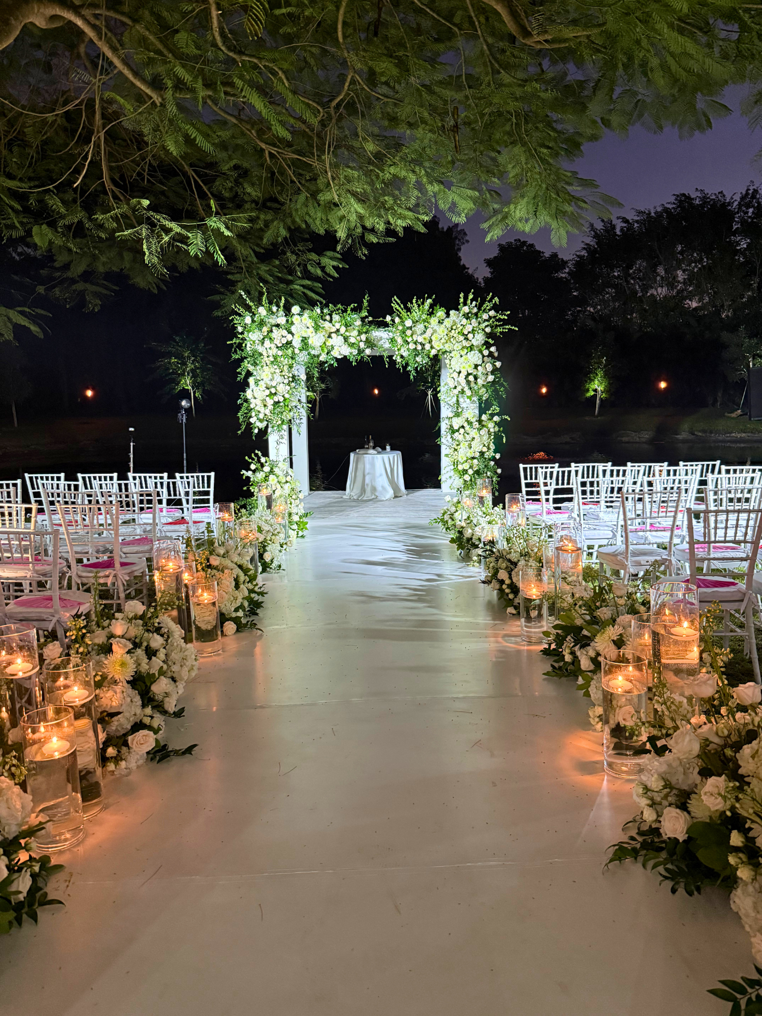 Modern White Floral Chuppah at an Elegant Evening Ceremony | Saint Patrick Palace White floral chuppah with candles lining the aisle during an elegant evening ceremony at Saint Patrick Palace in South Florida.