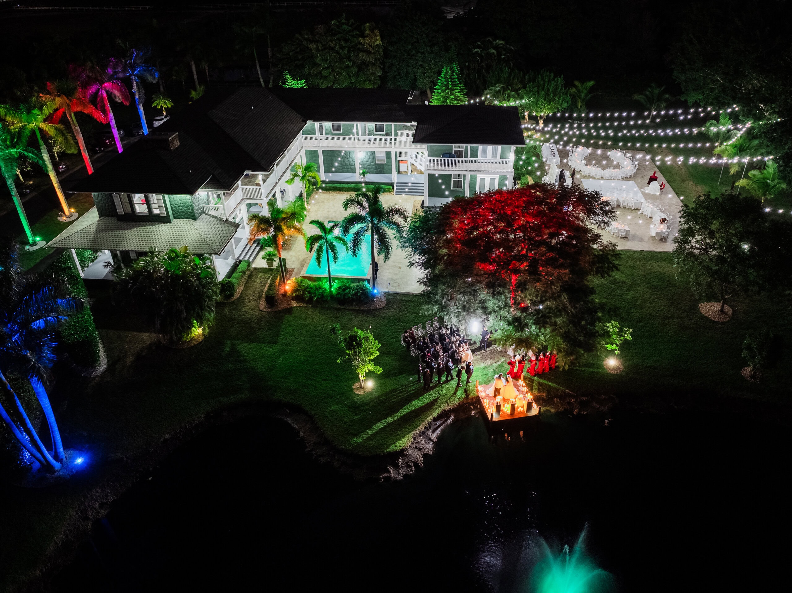 Nighttime aerial view of Saint Patrick Palace wedding venue with waterfront ceremony, estate lighting, and reception setup
