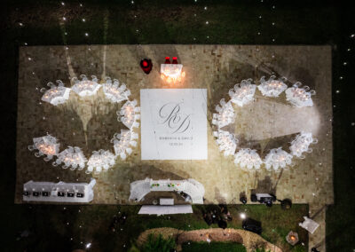 Outdoor wedding reception setup with circular seating, monogrammed dance floor, and ambient lighting at a private estate