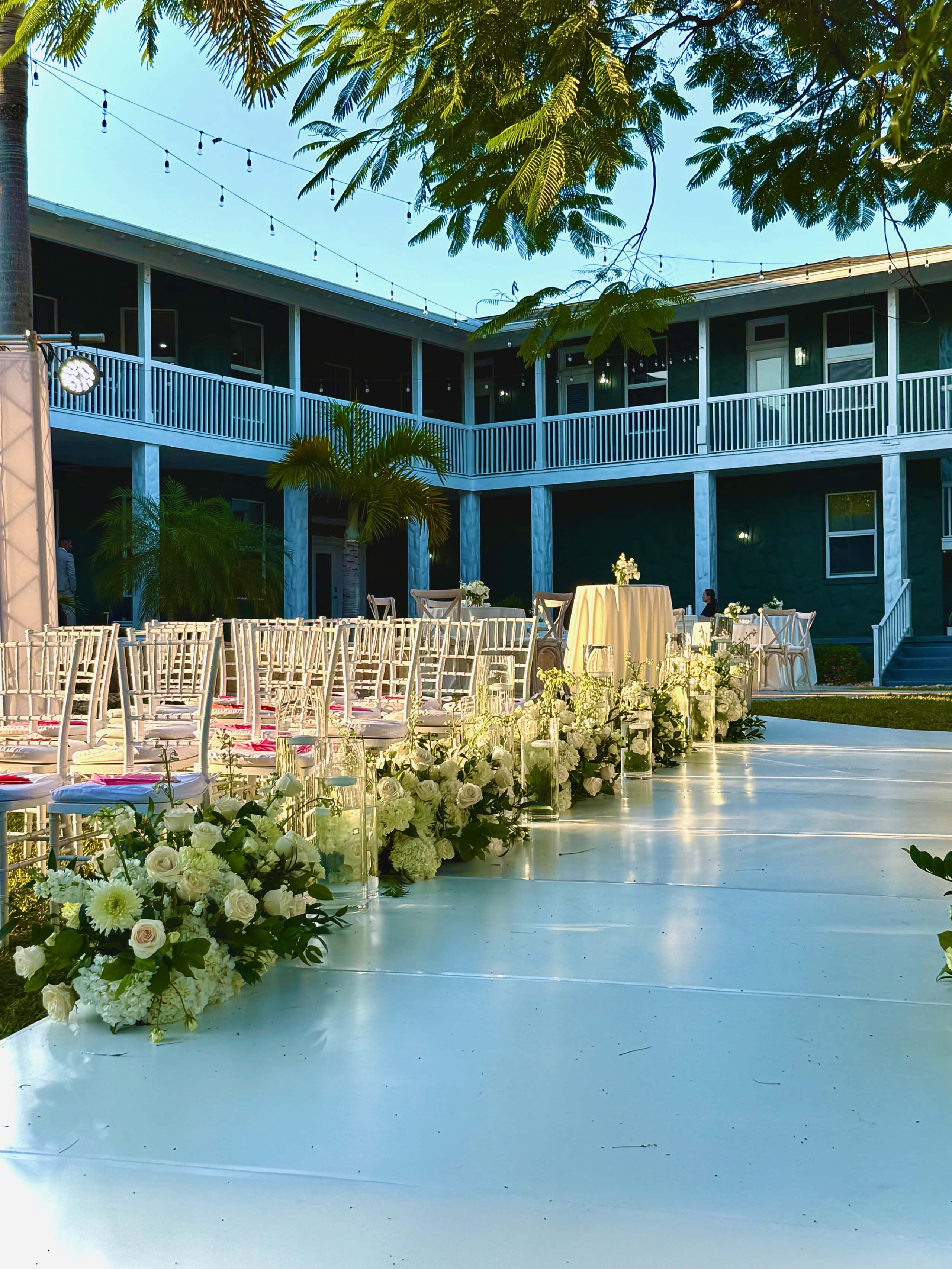 Outdoor South Florida homecoming wedding ceremony with white florals and a private home as the backdrop.