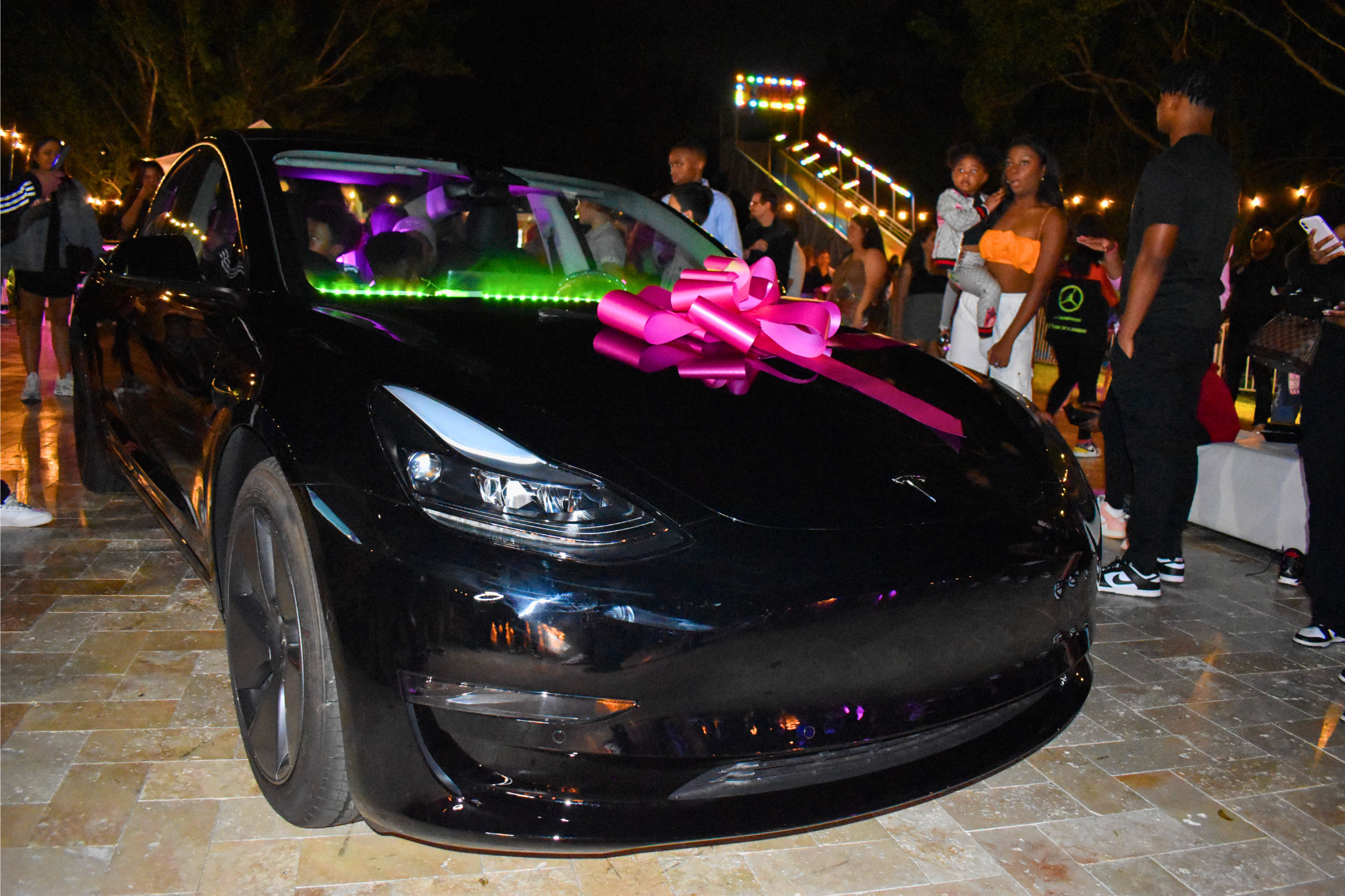 A black Tesla with a pink bow revealed as a luxury Sweet 16 gift at a private estate celebration.