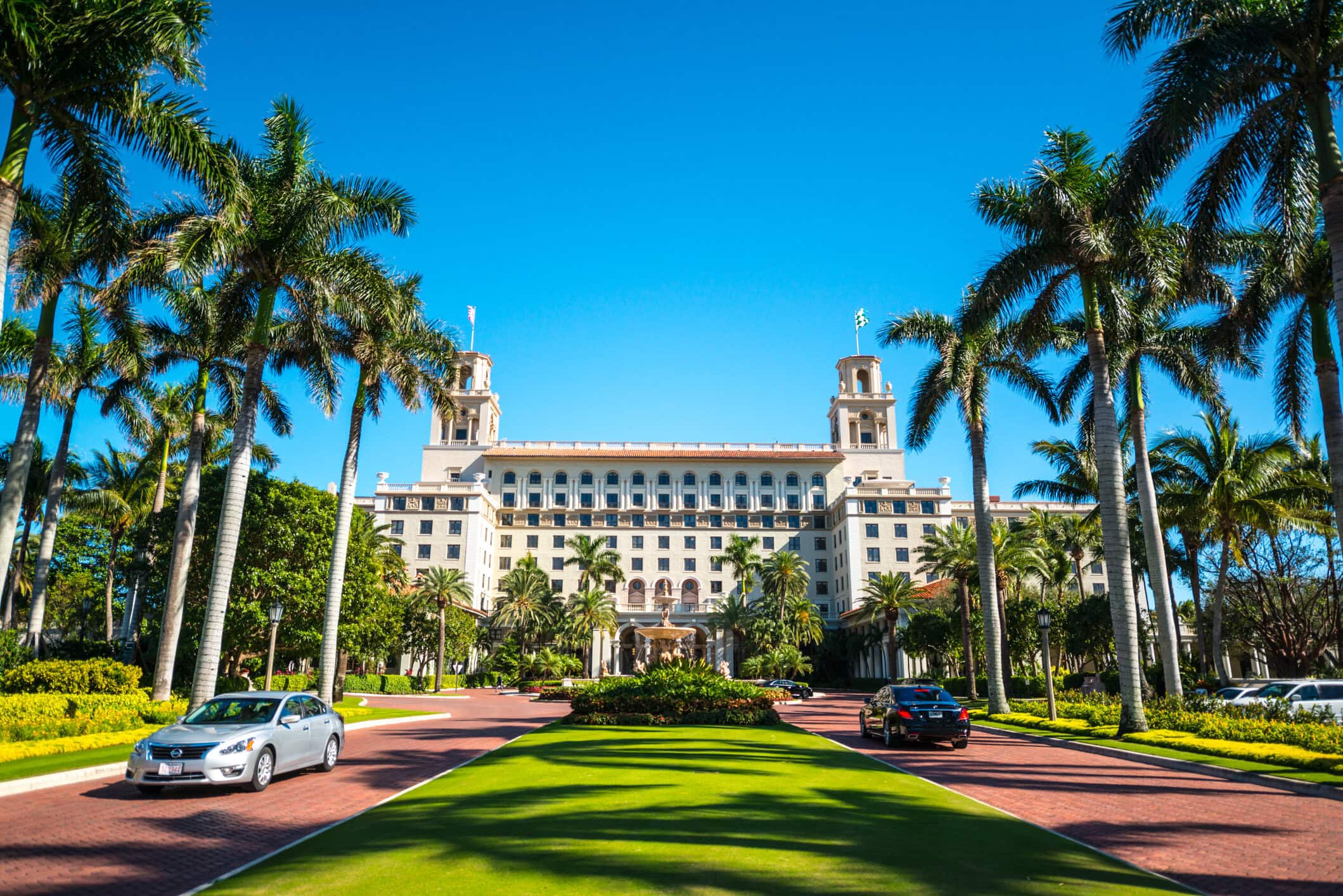 The Breakers Palm Beach luxury resort framed by palm trees, manicured lawns, and its grand historic architecture.
