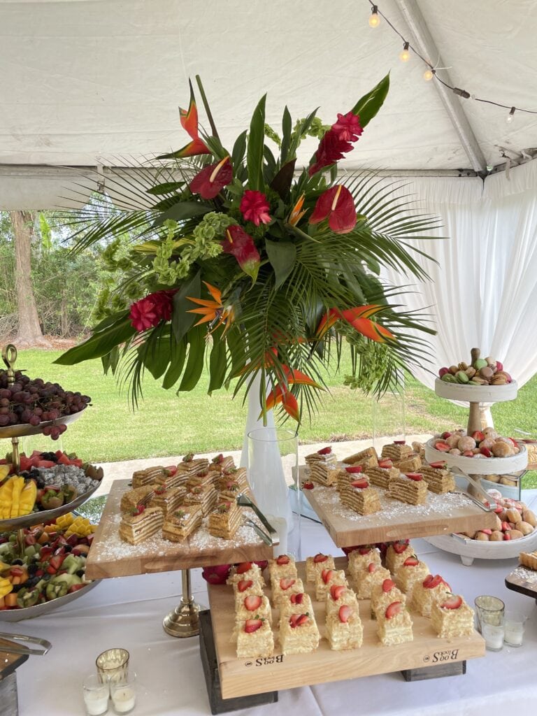Luxury dessert display with tropical flowers and pastries for a 60th birthday garden brunch in South Florida.