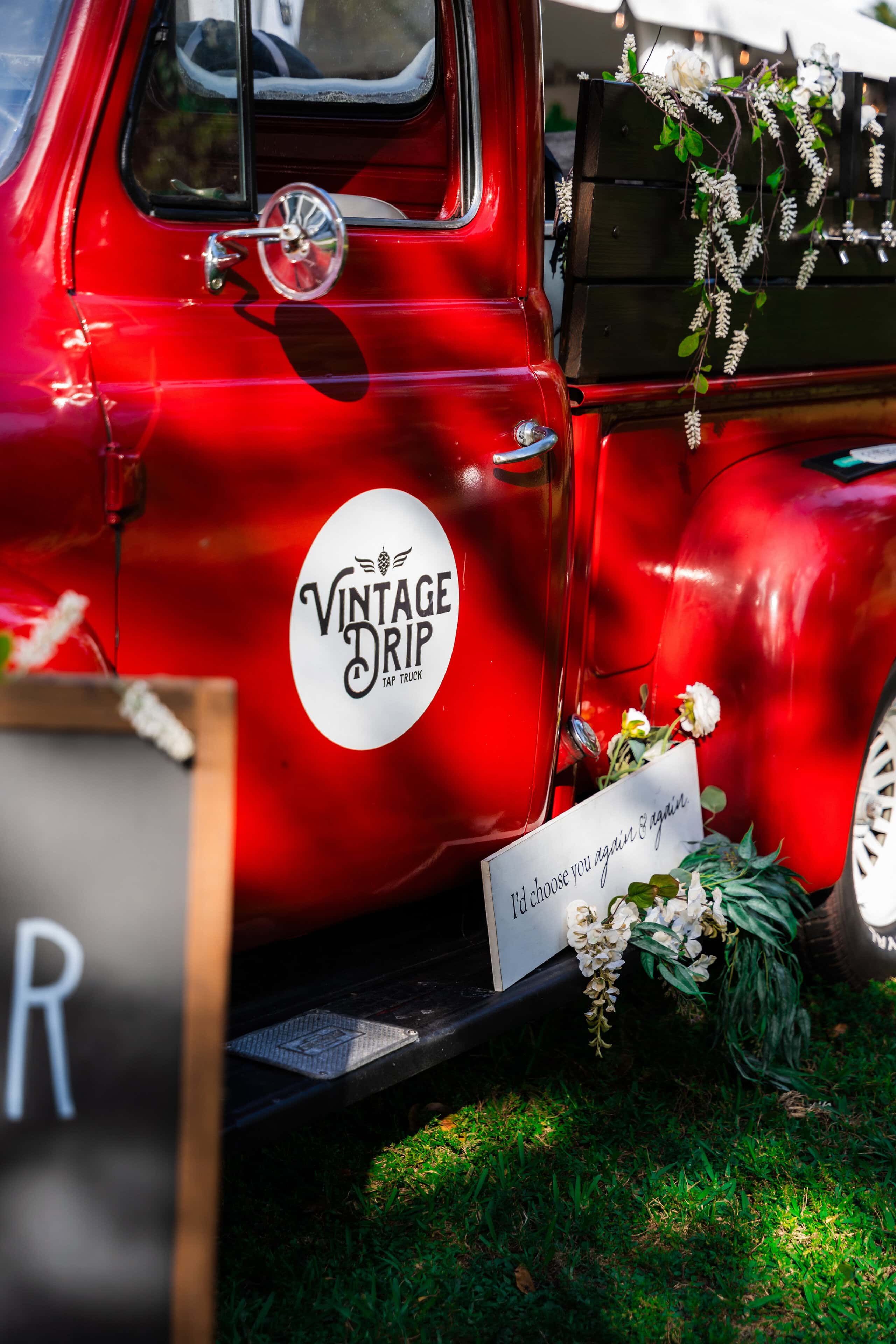 Vintage mobile wedding tap truck decorated with floral accents and personalized wedding signage.