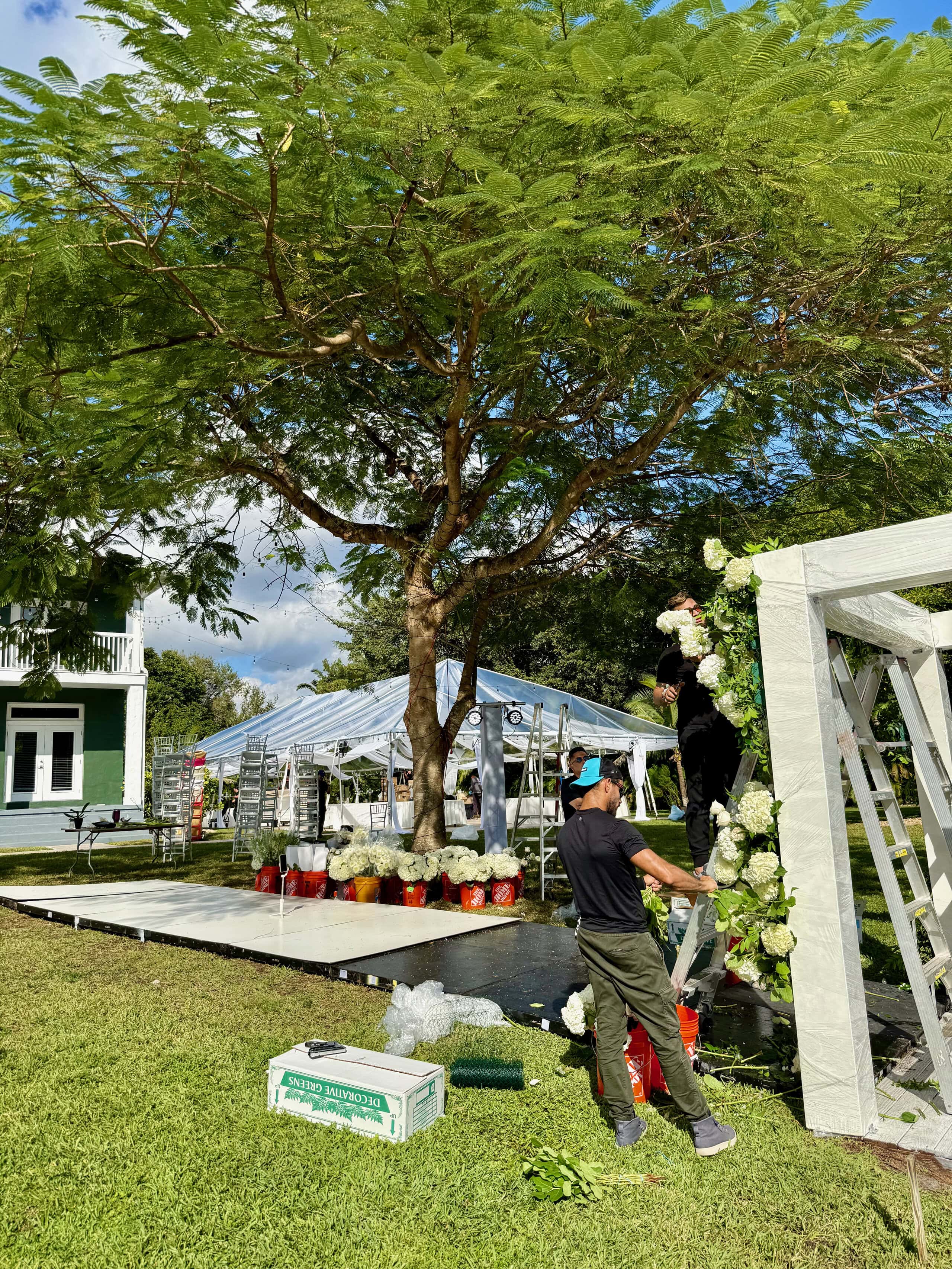 Wedding vendors setting up a floral ceremony arch and reception tent at Saint Patrick Palace.
