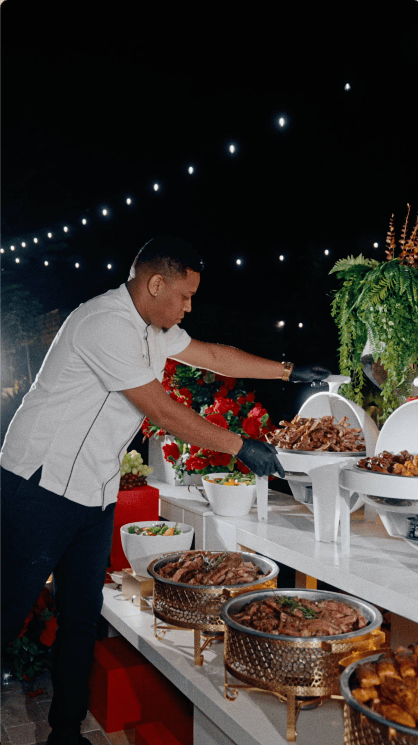 Chef preparing a wedding reception buffet under string lights at Saint Patrick Palace.