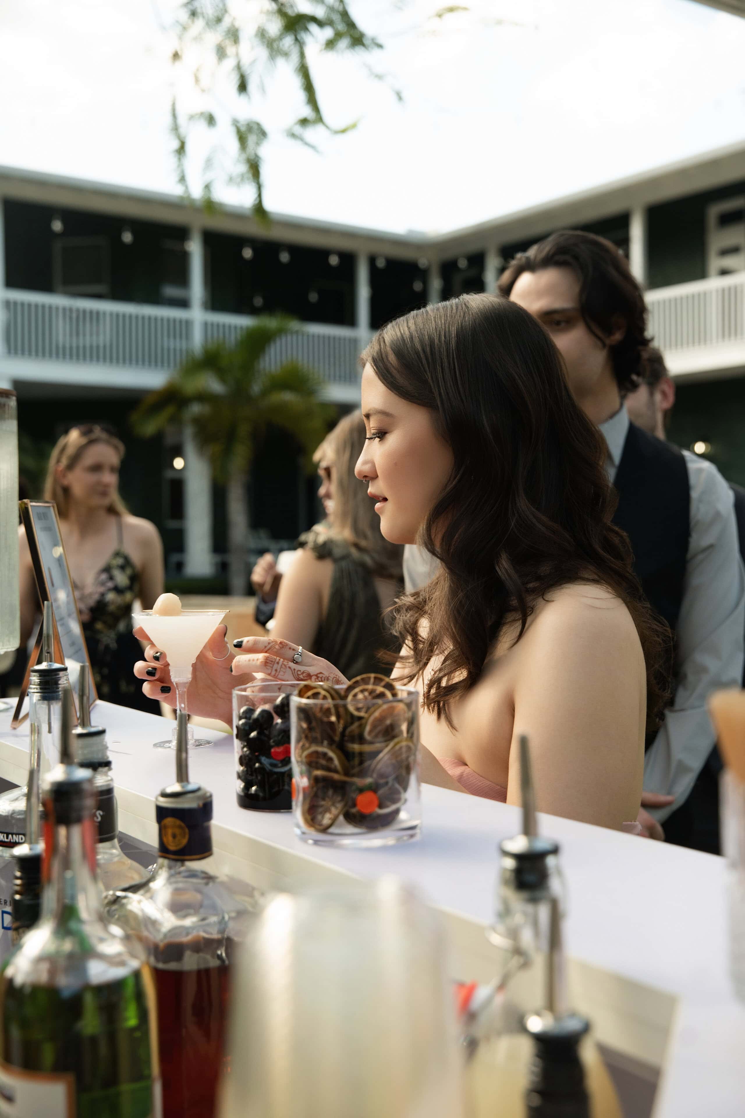 Guest enjoying a signature cocktail at an elegant outdoor wedding bar during cocktail hour at a South Florida wedding.