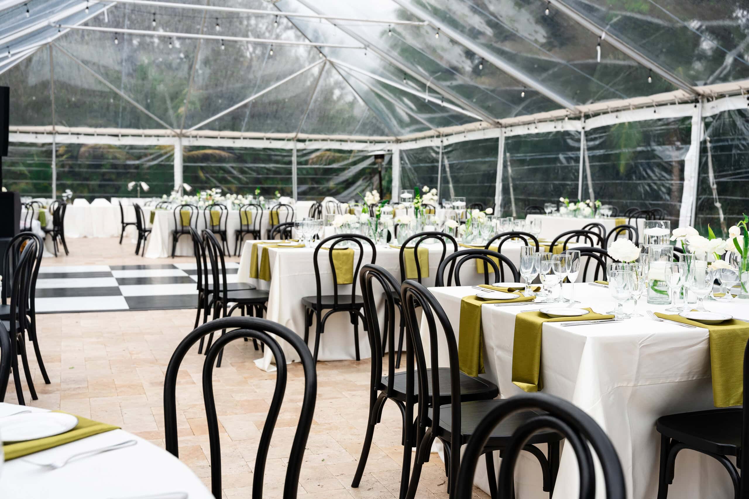 Clear-top tent with dining tables and dance floor at a South Florida wedding venue for 100 guests.