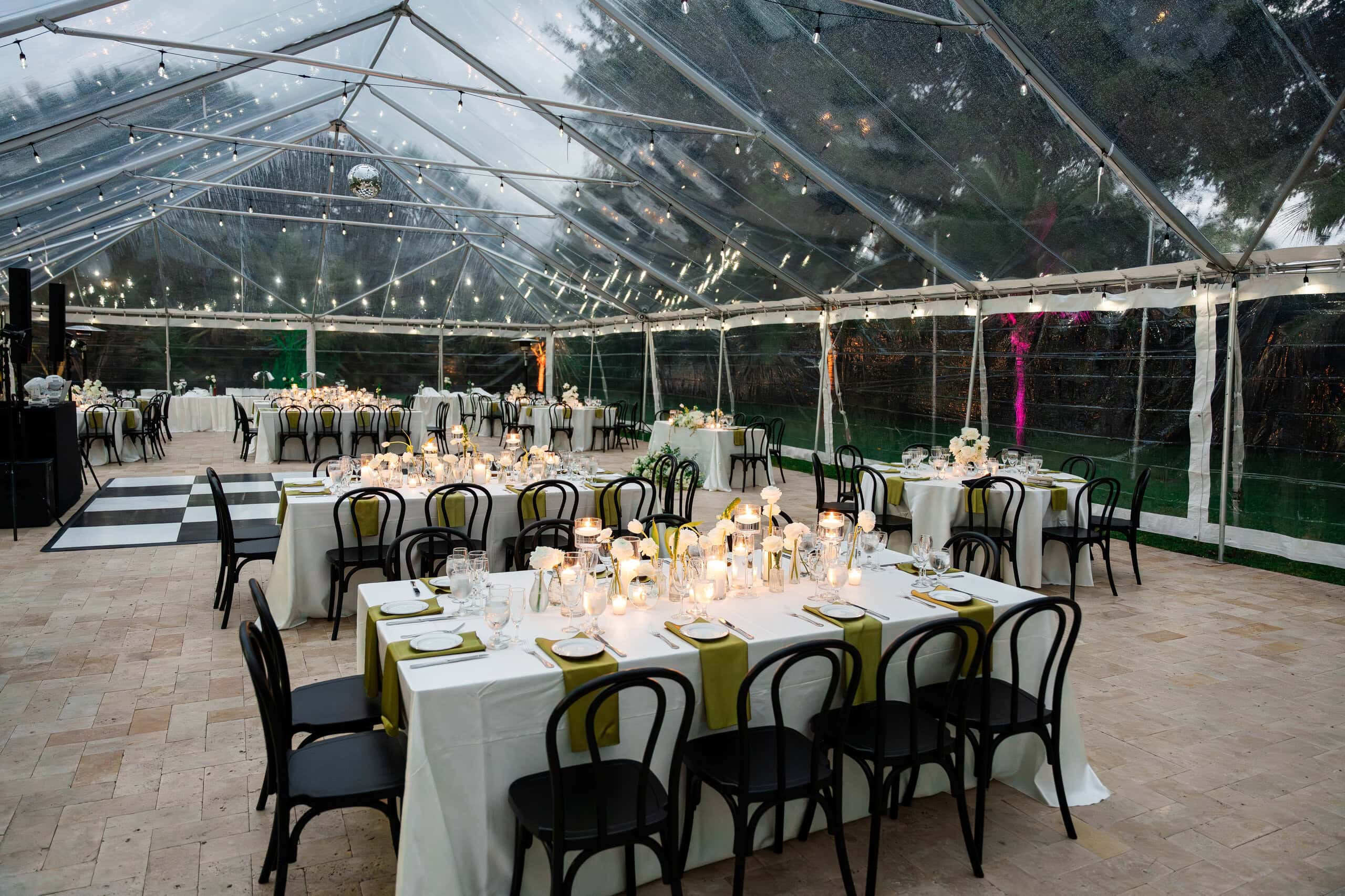 Clear-top tent with dining tables and dance floor at a South Florida wedding venue for 100 guests.