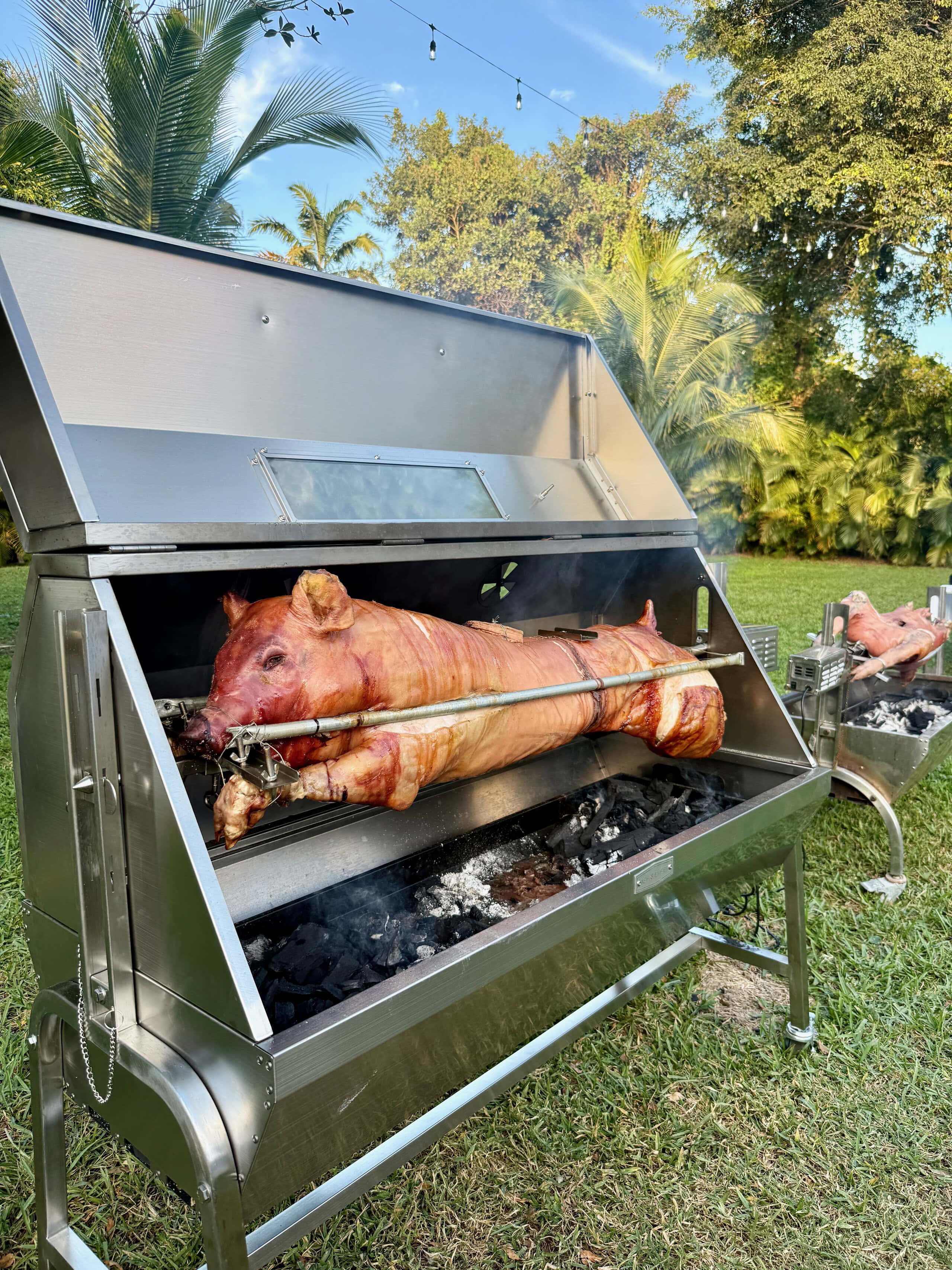 Whole hog roasting on a professional rotisserie grill during an outdoor wedding catering event at Saint Patrick Palace